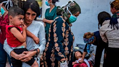 People attend to a woman collapsed as the body of a man killed during Turkish shelling in the area surrounding the Syrian Kurdish town of Ras Al-Ain arrives at a hospital in the nearby town of Tal Tamr following the announced ceasefire. AFP