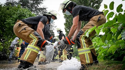 Firefighters move sandbags to defend against the rising water level of the Duessel, which has already flooded large areas and streets in Duesseldorf-Grafenberg, Germany.