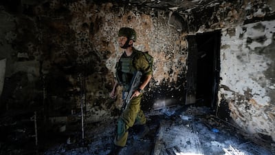 An Israeli soldier inspects a house damaged by Hamas militants in Kibbutz Kfar Azza, Israel. AP