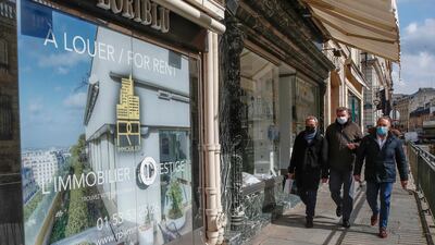People wearing masks to prevent the spread of the coronavirus walk past a vacant boutique for rent in Paris. AP Photo