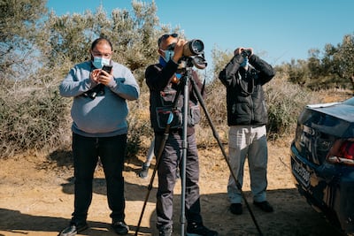 Hichem Azafzaf, centre, searches for ducks, cormorants, herons and flamingos while two ecologists from the Egyptian environmental ministry record data and search for birds alongside him. The National / Erin Clare Brown