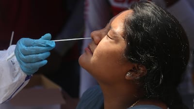 A woman undergoes a swab test at a bus stop in Bangalore, India, on April 7, 2021. EPA