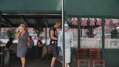 A woman walks past a life-sized cut-out of Britain's Queen Elizabeth II outside the British-owned business of Tea & Sympathy in Manhattan’s Greenwich Village in New York. APF