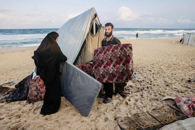 A Palestinian family move their belongings to take shelter from the rain at a makeshift camp on the Gaza coast. AFP