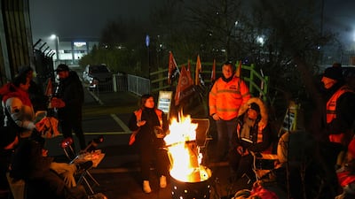 Striking workers gather around a fire pit. Bloomberg