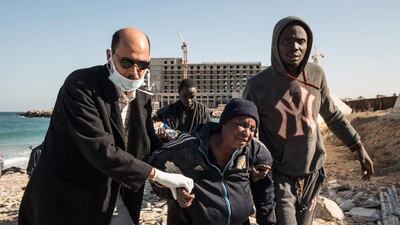 Members of the Libyan Red Crescent help a woman who was aboard a boat that arrived to the shore of the Andalus district of the capital, Tripoli. Taha Jawashi / AFP