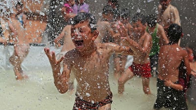 A Syrian boy reacts as he gets sprayed with water in a portable swimming pool set up by volunteers, at a camp for the displaced in the rebel-held town of Kafr Yahmul in the northern countryside of Idlib on August 10, 2022. (Photo by aaref watad / AFP)