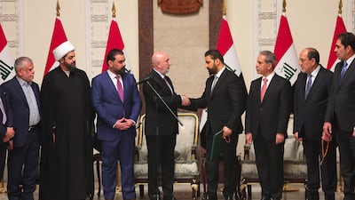 Iraq's President Nizar Amede, centre left, shakes hands with newly designated Iraqi prime minister Ali Al Zaidi in the company of some of the country's political leaders in Baghdad. AFP