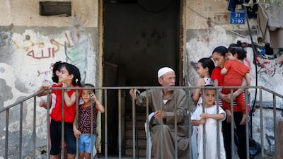 A Palestinian sits outside a home surrounded by children in Gaza City. EPA