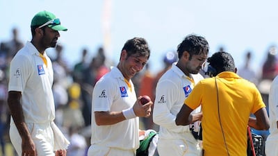 Yasir Shah, centre, leaves the field with the match ball after his seven wickets. Ishara S Kodikara / AFP