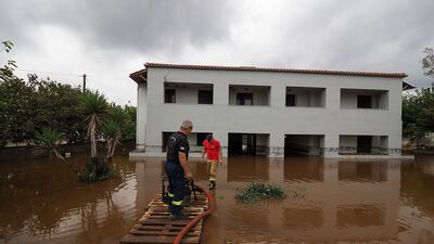 Firefighters pump water from a property in the village of Agia Anna. AP Photo