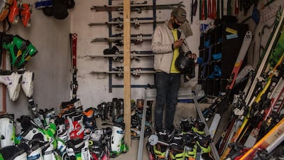 Said Ali Shah Farhang, 29, sorts through skiing equipment in his office, wearing a mask to protect from coronavirus risks.