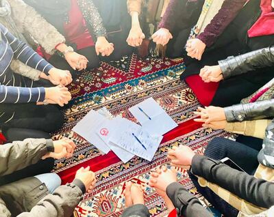 Women hold hands at an indoor protest. S Hamidi