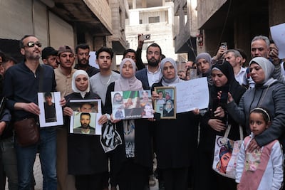 People hold photos of their relatives killed in the Tadamon massacre, as Syrians celebrate after the arrest of the main accused. EPA
