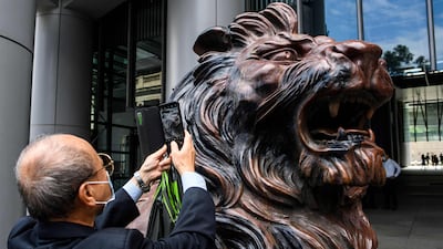 A man takes a photo of a lion statue outside HSBC bank headquarters building in Hong Kong. AFP