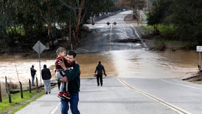 Marcial Calleja Aguirre runs with son Oliver as it starts to rain at the Silvas crossing at Uvas Creek in Gilroy. EPA