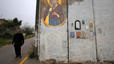 A man walks along a wall decorated with Christian icons and votive offerings in the West Bank city of Bethlehem. EPA
