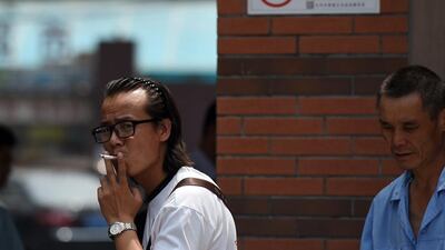 A man smoking near a new sign that bans smoking outside a children's hospital in Beijing on June 1, 2015. Greg Baker/AFP Photo