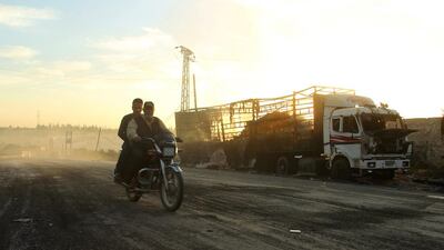 Men drive a motorcycle near a damaged aid truck after an air strike on the rebel held Urm Al Kubra town, western Aleppo city, Syria on September 20, 2016. Ammar Abdullah/Reuters