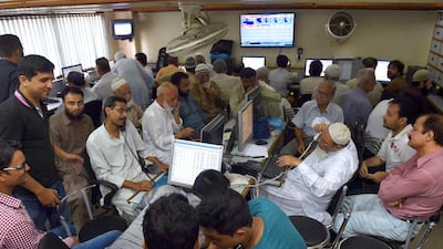 Pakistani stockbrokers talk on phones as they watch share prices on a monitor. The Karachi Stock Exchange declined 4 per cent to close at 33,117.53 points on Monday. Rizwan Tabassum / AFP