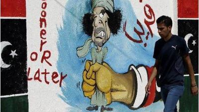 A Libyan walks past graffiti depicting former Libyan leader Muammar Qaddafi in Tripoli last month. Joseph Eid / AFP Photo