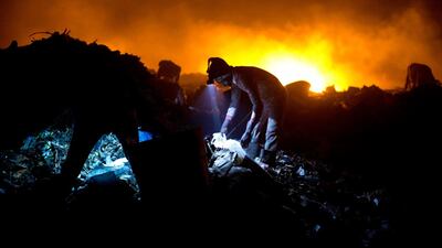 Trash scavengers work with headlamps as they look for useful items. AP Photo