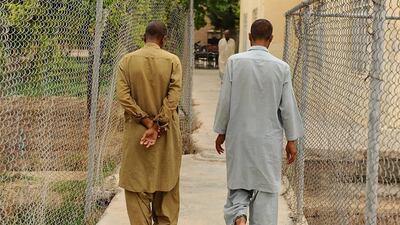 Patients who have been chained together for security purposes walk along a fenced pathway in the centre.