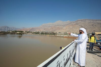 Mohammed Al Shahhi points at the flooded cemetery in Al Ghalilah village. Leslie Pablo for The National