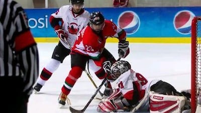 UAE's Abdullah Al Harmodi, No 23, tries to jam the puck past Eissa Sultan Albloushi, the Bahrain goalkeeper.