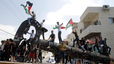 Palestinian youths sit on the 'The Key of Return', which was exhibited at the seventh Berlin Biennale, upon its return to the Aida refugee camp near Bethlehem. Musa Al Shaer / AFP Photo