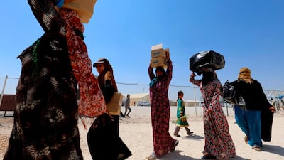 Syrian women, displaced from their homes in Deir Ezzor, carry boxes of clothes as part of humanitarian aid provided by UNICEF. AFP