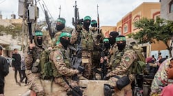 Hamas fighters patrol a street before they handover three Israeli hostages to a Red Cross team in Deir el-Balah, central Gaza, on February 8, 2025. Hamas militants handed over three Israeli hostages on February 8, as part of the fifth exchange under a fragile Gaza ceasefire, with 183 prisoners held by Israel due to be released later in the day. (Photo by Eyad BABA / AFP)