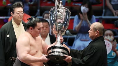 Hakuho receives the championship trophy at the awards ceremony after beating Terunofuji to finish with a perfect 15-0 record for his 45th career tournament championship. AFP