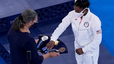Simone Biles, of the United States, picks up her bronze medal after the women's artistic gymnastics balance beam final.