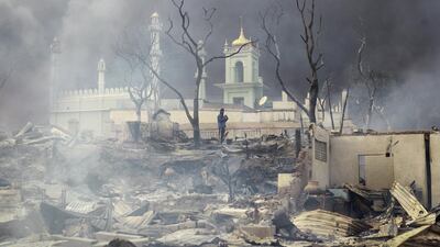 A man stands in front of a mosque as it burns in Meikhtila, Myanmar March 21, 2013. Soe Zeya Tun / Reuters