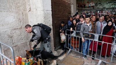 Palestinians stand behind a police barricade as an Israeli police dog sniffs at the Damascus Gate near the attack site in the Old City of Jerusalem on March 18, 2018. Abir Sultan / EPA