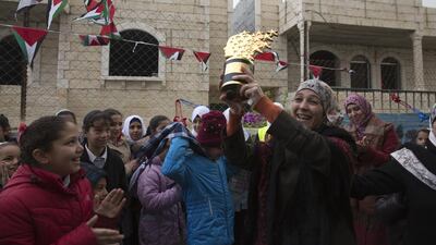 Palestinian teacher Hanan Al Hroub shows her Global Teacher trophy to Samiha Khalil students and teachers on March 20, 2016, who welcomed her back on March 20,2016. Heidi Levine for The National