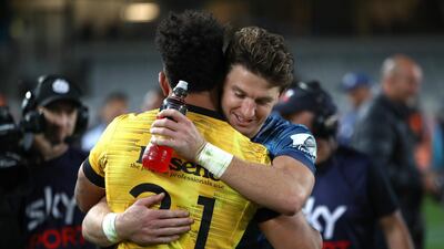 Beauden Barrett of the Blues hugs Ardie Savea of the Hurricanes. Getty