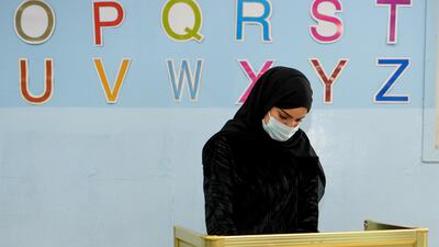 A Kuwaiti woman wearing a protective mask cast her vote at a polling station in Kuwait City. EPA