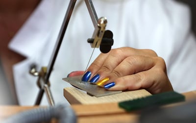 Using a jeweller's saw to cut a silver metal plate. Pawan Singh / The National