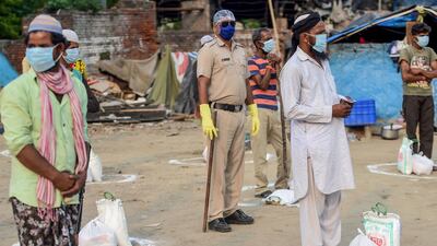 People stand inside marked circles maintaining social distancing to get groceries distributed by police personnel during a government-imposed nationwide lockdown in Faridabad. AFP