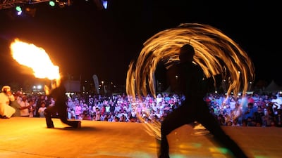 Visitors watch a fire performance on the open air stage at the Al Gharbia Watersports Festival.