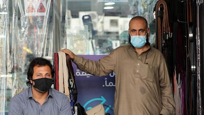 Two traders wear face masks at their stall in Satwa
