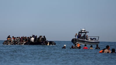 A French police boat approaches a group of migrants on an inflatable dinghy trying to cross the English Channel to Britain. Reuters