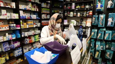 A pharmacist wearing a face mask works in western Tehran on Saturday. Iran is preparing for the possibility of "tens of thousands" of people needing to be getting tested. Vahid Salemi / AP Photo