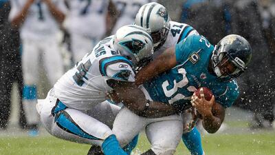 Jacksonville Jaguars' Maurice Jones-Drew (32) is tackled by Carolina Panthers' Captain Munnerlyn (41) and Jason Williams (54) during the third quarter of an NFL football game in Charlotte, N.C., Sunday, Sept. 25, 2011. Bob Leverone / AP Photo