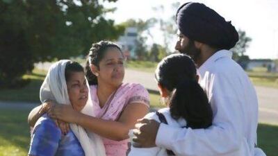 People console each other near the Sikh Temple of Wisconsin where a gunman opened fire during a service before being shot dead by a policeman.