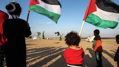 Palestinians hold their national flag as youths practice their parkour skills at the Israel-Gaza border in the southern Gaza Strip. Said Khatib / AFP