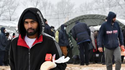A migrant carries food after receiving provisions from the Red Cross. AFP