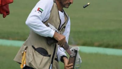 Emirati shooter Sheikh Ahmed bin Hasher al-Maktoum, a member of Dubai's ruling family, empties cartridges from his rifle during the men's trap shooting qualifications.